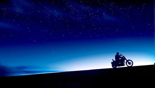 Man riding motorcycle against sky at night