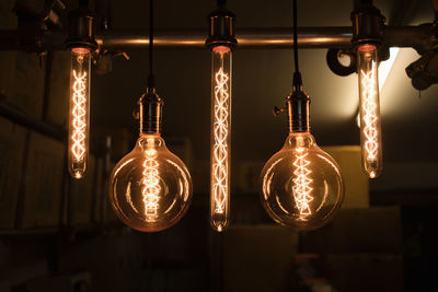 Close-up of illuminated light bulbs hanging from ceiling