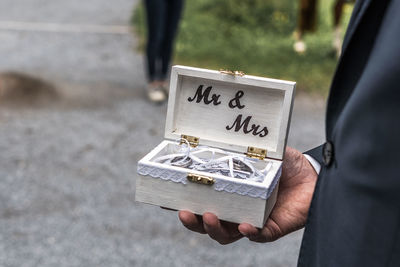 Midsection of man holding rings in box during wedding ceremony