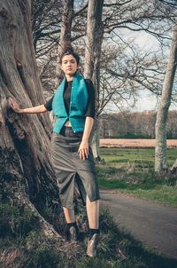 Portrait of happy young woman standing on tree trunk