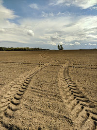 Tire tracks on field against sky