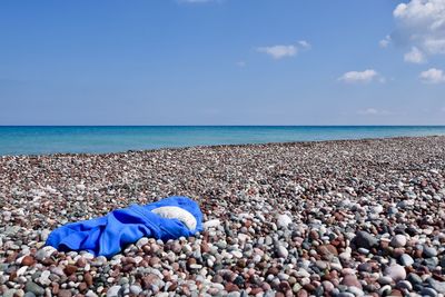 Close-up of pebbles on beach against blue sky