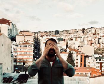 Woman photographing against buildings in city