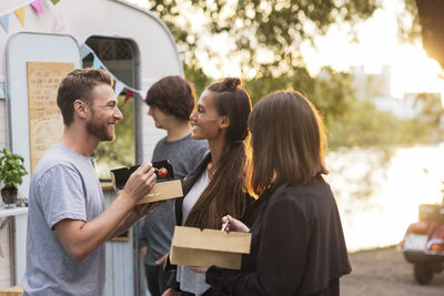 Happy friends talking while having salad outside food truck