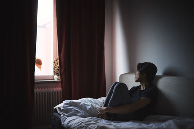 Pensive man sitting on sofa and looking through window