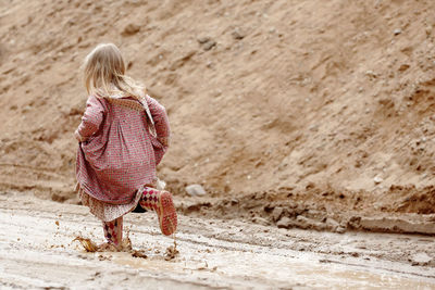 Rear view of girl walking on muddy road