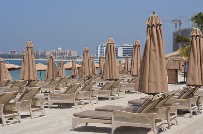 Panoramic view of empty chairs at beach against clear sky