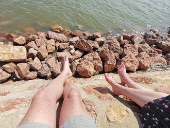 Low section of people sitting on rock at beach