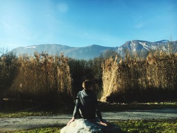 Full length of man sitting on land against sky