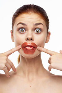 Close-up portrait of young woman making face against white background