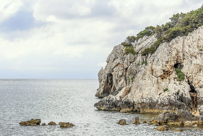 Rock formation by sea against sky