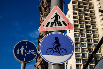 Low angle view of road sign against blue sky