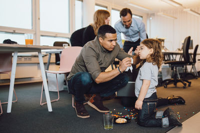 Businessman crouching by son against colleagues in creative office