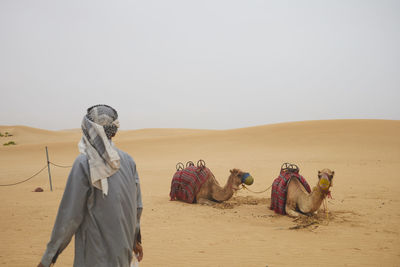 Rear view of man standing at desert against clear sky