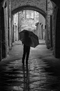 Man walking under umbrella in alley