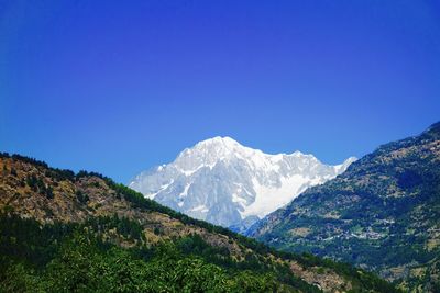 Scenic view of snowcapped mountain against blue sky