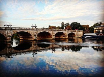 Arch bridge over river against sky