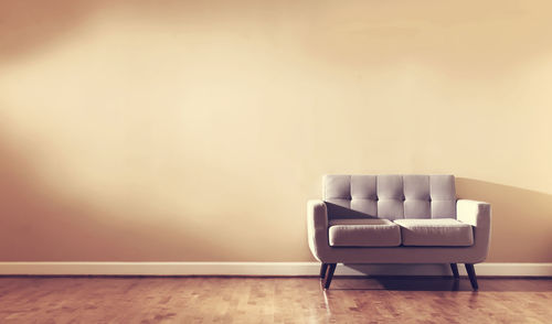 Empty chair on hardwood floor against wall at home