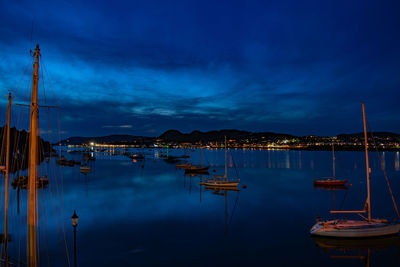 Sailboats moored in harbor against sky