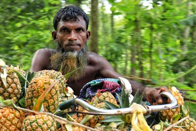 Portrait of senior man carrying pineapple to local market by bicycle 