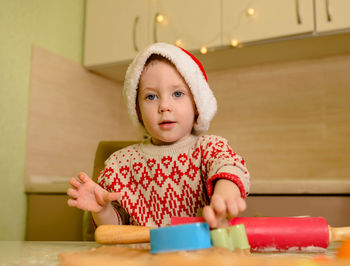 Helper in santa's hat and red sweater making cookies at home. xmas