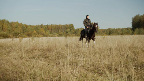 Full length of woman riding horse on field