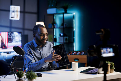 Side view of man using laptop while sitting on table