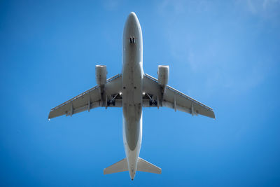 Low angle view of airplane flying against clear blue sky