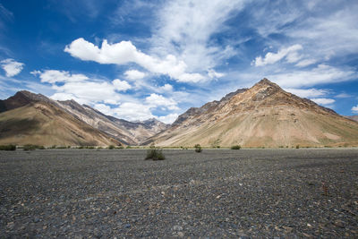 Scenic view of road by mountains against sky