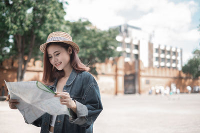 Young woman wearing hat standing against city in background