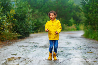 Full length portrait of happy boy standing on road