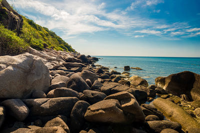 Rocks on shore by sea against sky