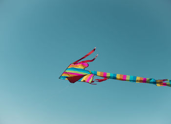 Low angle view of colorful kite flying in clear blue sky