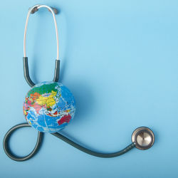 Close-up of stethoscope with globe over blue background
