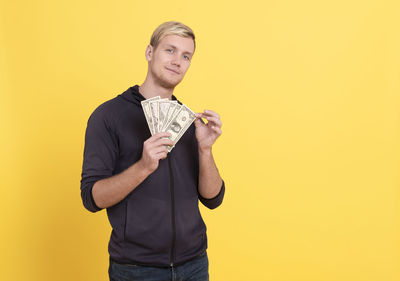 Portrait of young man standing against yellow background
