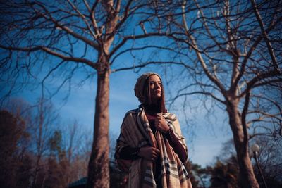 Man standing by bare tree against plants