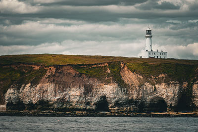 Lighthouse by sea against sky