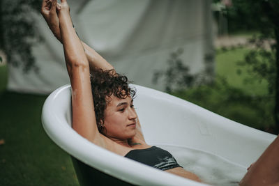 Young woman sitting in bathtub outdoors