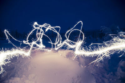 Close-up of illuminated snow against sky at night