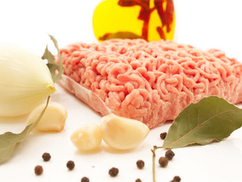 Close-up of meat with ingredients on white background