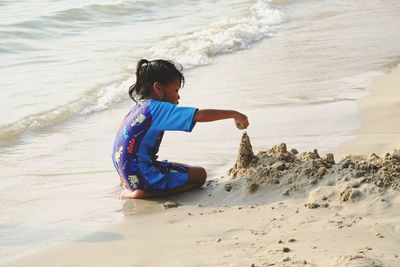 Girl making sandcastle on shore at beach