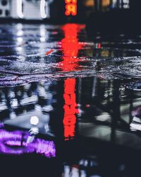 Reflection of illuminated city on wet road during rainy season