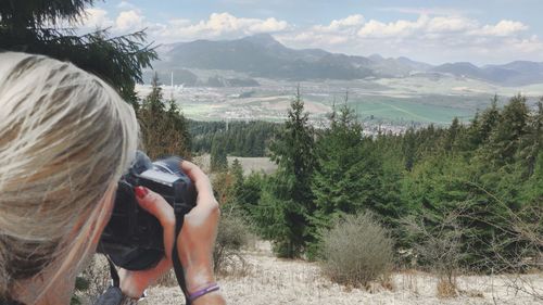 Cropped image of woman photographing trees and mountains