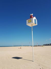 Information sign on beach against clear blue sky