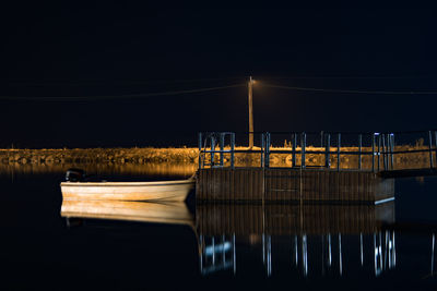 Reflection of illuminated bridge in river against clear sky at night