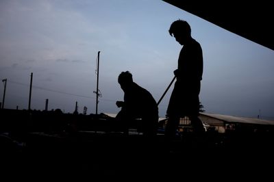Low angle view of silhouette people against sky at sunset
