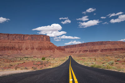 Road leading towards mountain against sky