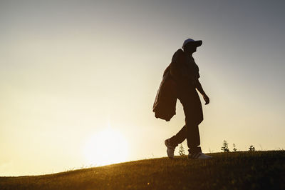 Low angle view of silhouette man walking on land against clear sky during sunset