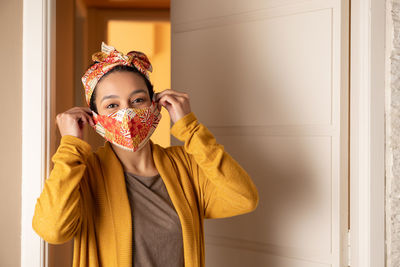 Portrait of smiling woman wearing mask standing at home