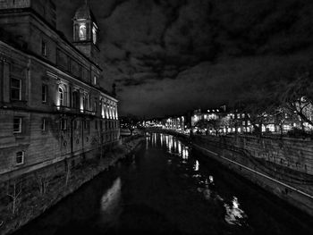 Canal amidst illuminated buildings in city at night